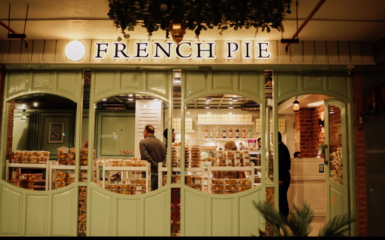 The French Pie shop front at night — lit signage above sage-green doors