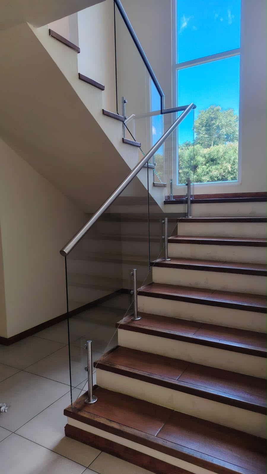 Escalera con baranda de vidrio y ventanal